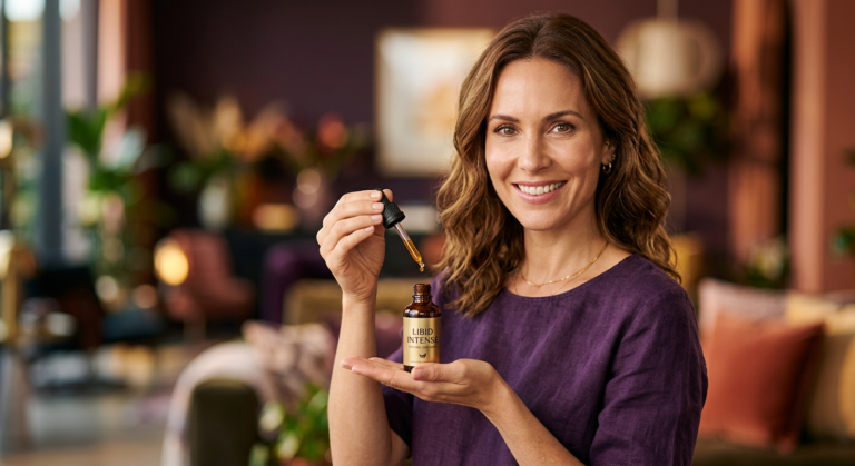 Mulher confiante e sorridente segurando frasco de Libid Intense em gotas, simbolizando energia e aumento da libido feminina.